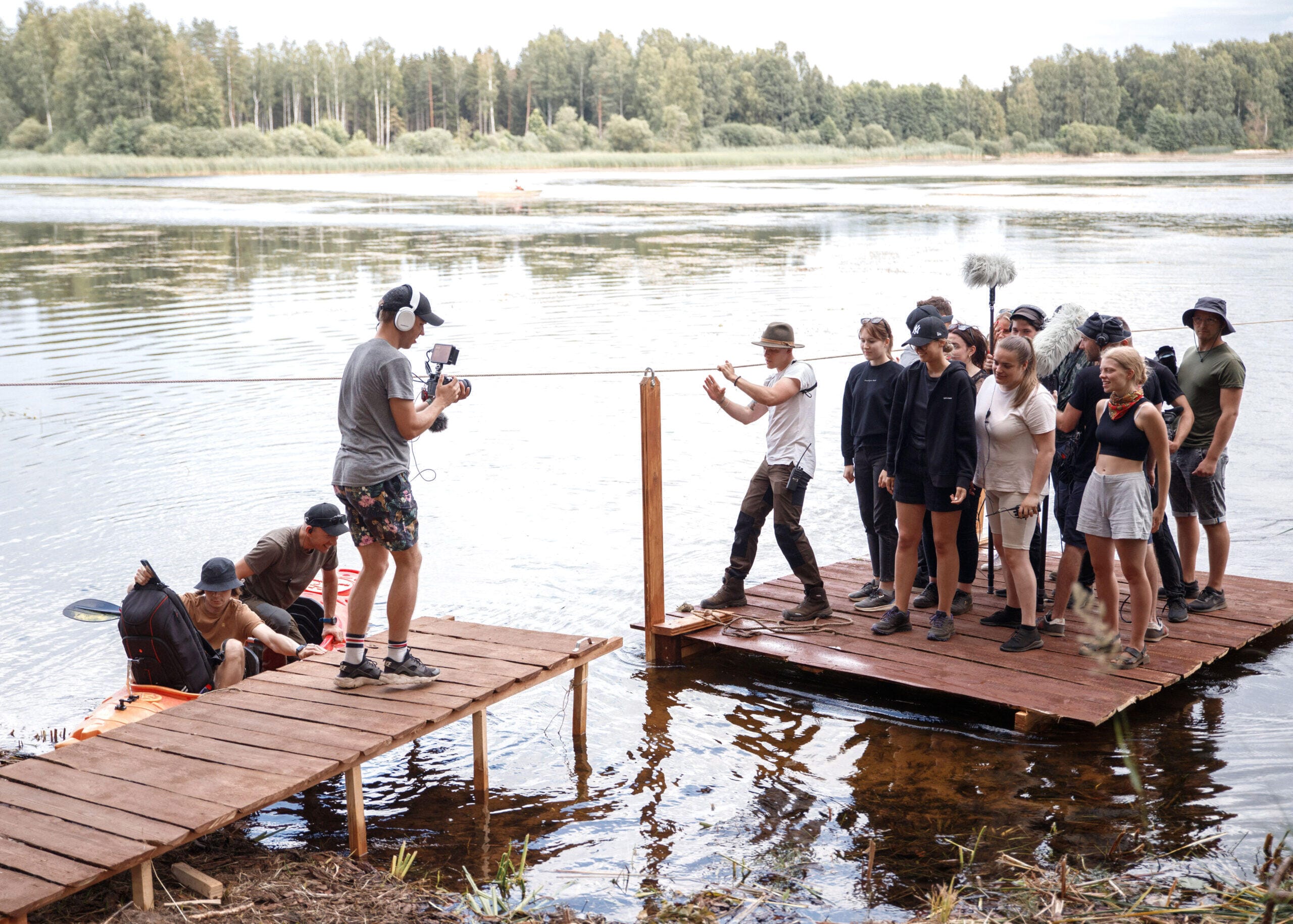 Nuotraukoje keli žmonės valtimi ar kajaku plaukia ežeru. Kadras atspindi Filmspace dokumentikos filmavimo ir kelionių aftermovie filmavimo paslaugas, kuriose video kūrėjas fiksuoja natūralią nuotykių atmosferą.