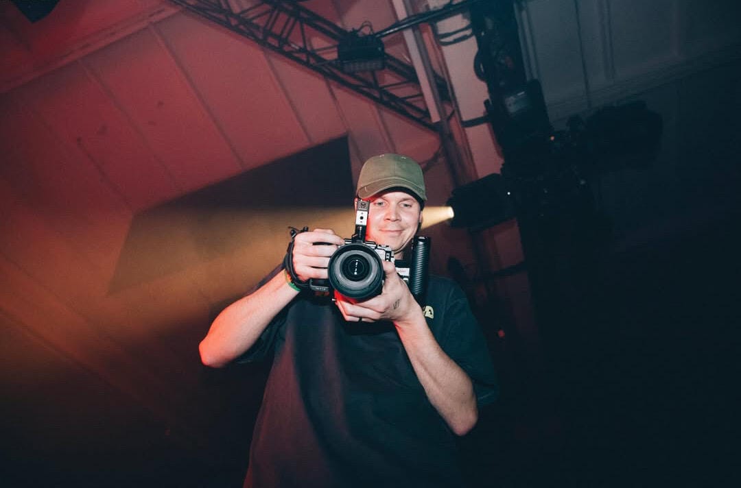 Video operatorius filmuoja raudonai apšviestoje erdvėje – muzikinių klipų filmavimas