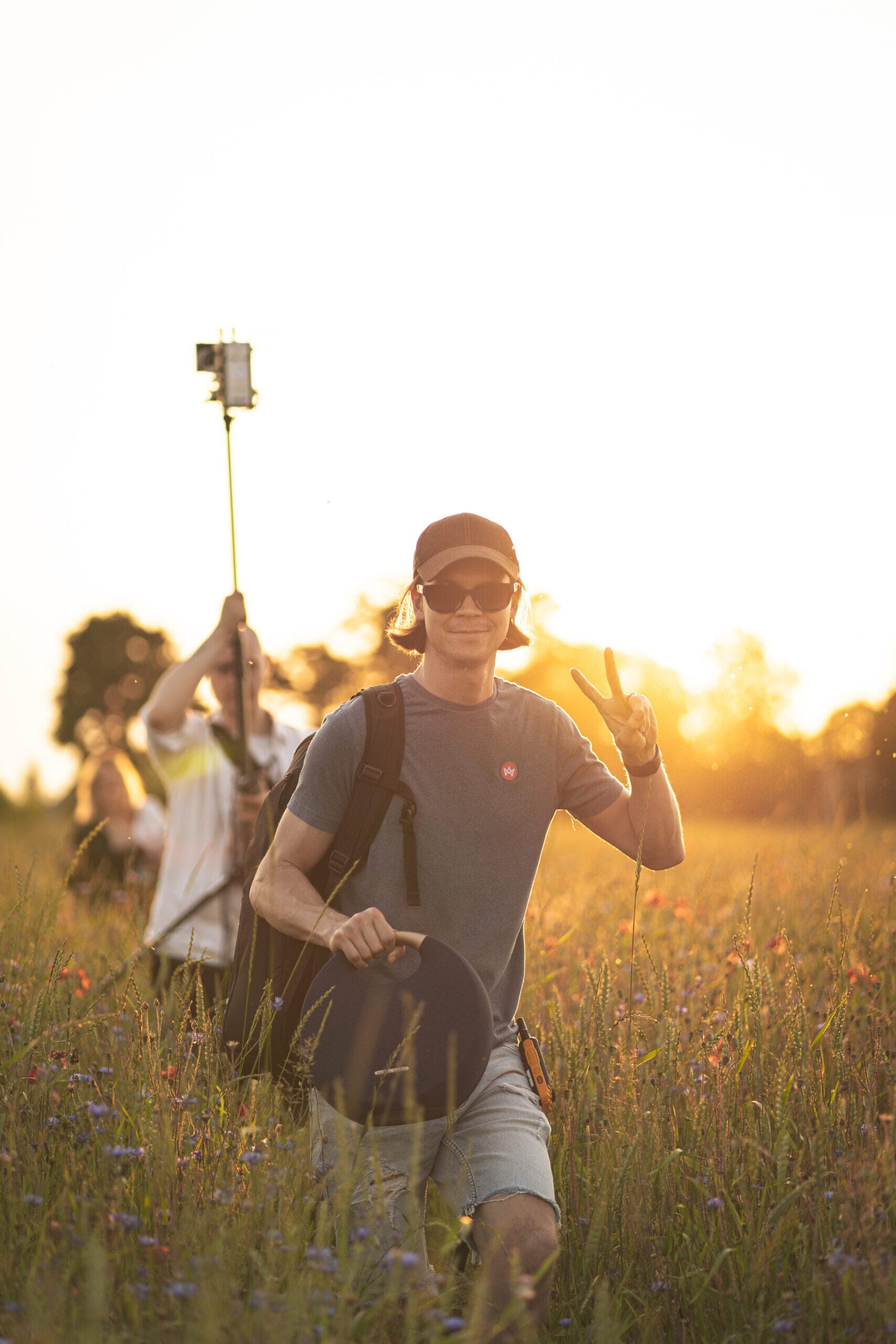 Video operatorius Benas Černiauskas filmuojantis lauke saulėlydžio metu